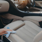 Keeping driving space clean and hygienic. Male hand disinfecting fabric car seat with microfiber cloth and detergent, cropped shot of carwash worker cleaning auto upholstery