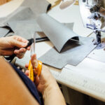 Top view of the hands of a woman preparing in the sewing machine a piece of leather to upholstering the interior car components in a upholstery factory