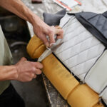 Close up of person fitting car upholstery and cutting extra threads with scissors, copy space