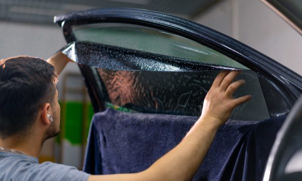 Male car service worker glue window tinting in luxury car detailing car repair the concept of love for cars and a protection